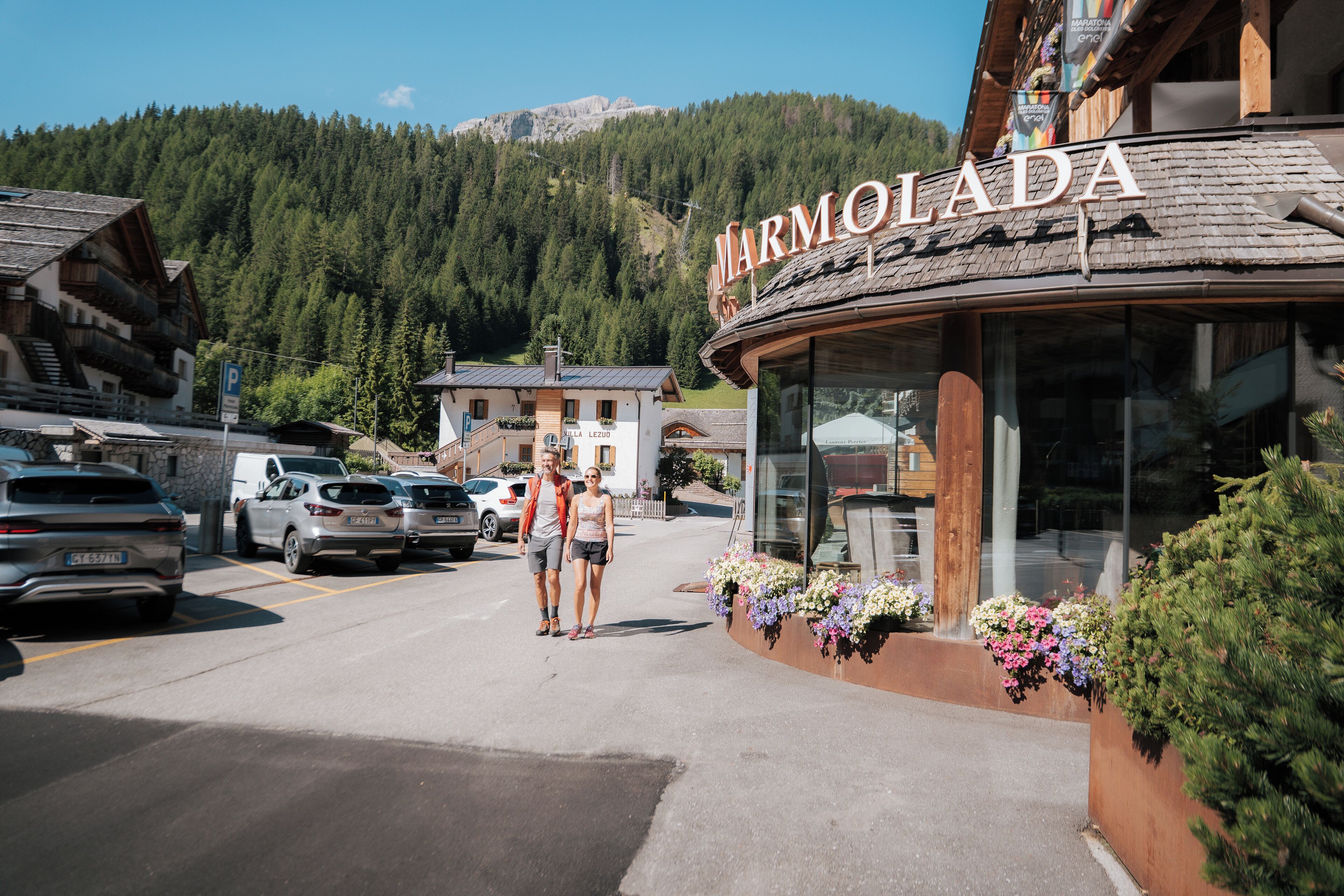 A building with a sign reading "MARMOLADA" and a parking area with cars.