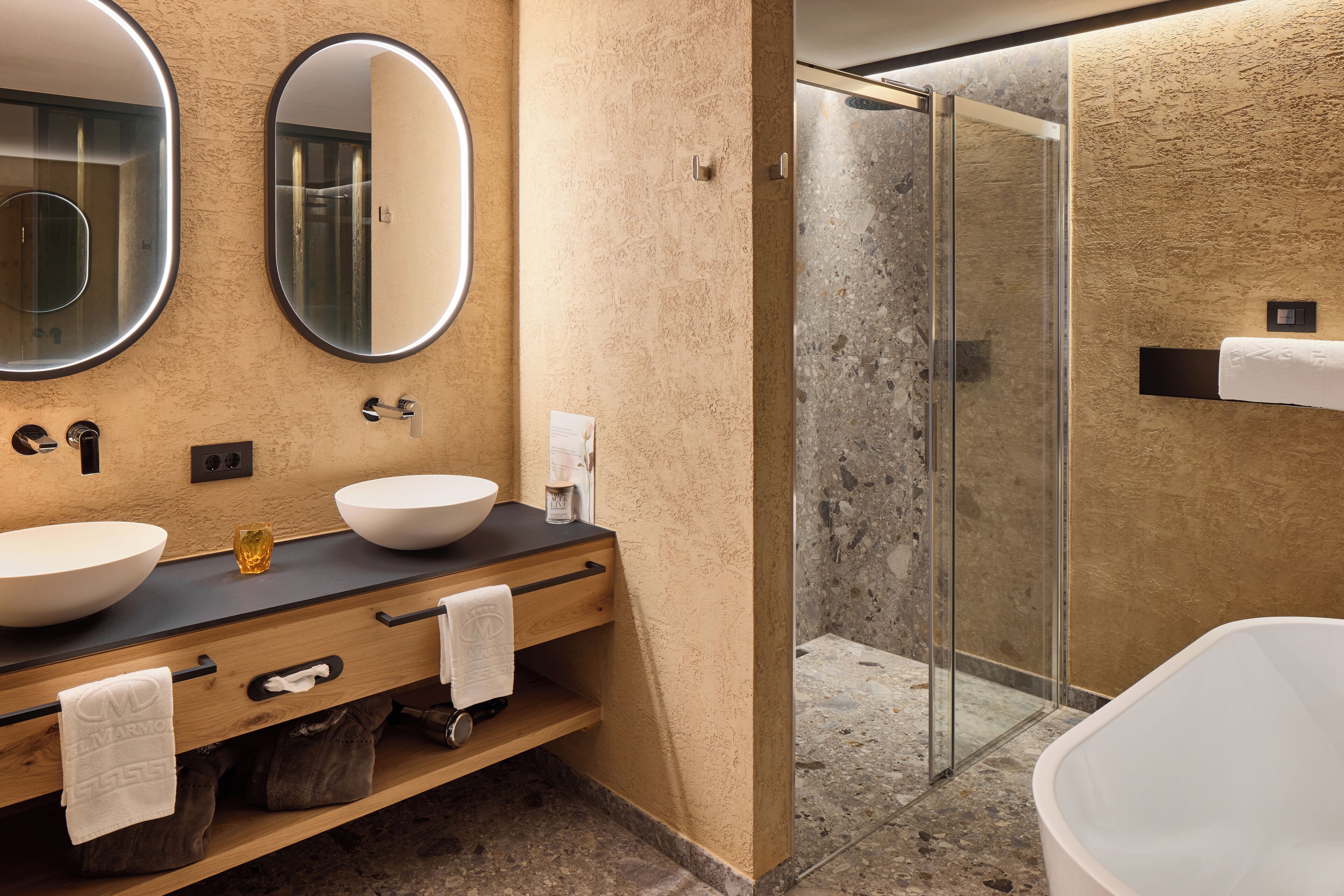 A modern bathroom with two sinks, a glass shower enclosure, and a bathtub.