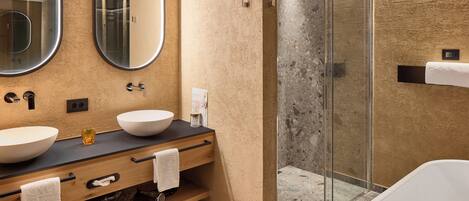 A modern bathroom with two sinks, a glass shower enclosure, and a bathtub.