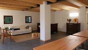 A spacious living room with a wooden ceiling, a white sofa, a wooden table, and a dark wooden cabinet. - Civico 1A1 (Santa Maria di Sala)