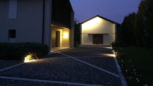 A modern building with a sloped roof, a visible garage door, and a well-lit entrance. - Civico 1A1 (Santa Maria di Sala)