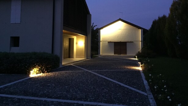 A modern building with a sloped roof, a visible garage door, and a well-lit entrance. - Civico 1A1 (Santa Maria di Sala)