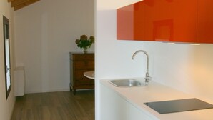 A modern kitchen with white cabinetry, a wooden ceiling, and a small island with a sink. - Civico 1A1 (Santa Maria di Sala)