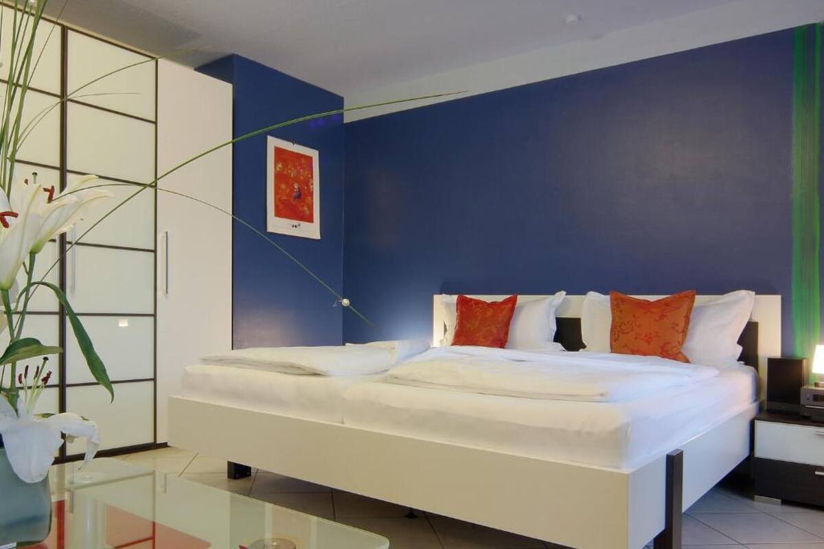 Une chambre d’hôtel moderne avec un grand lit, une table basse en verre et une vue sur la ville.