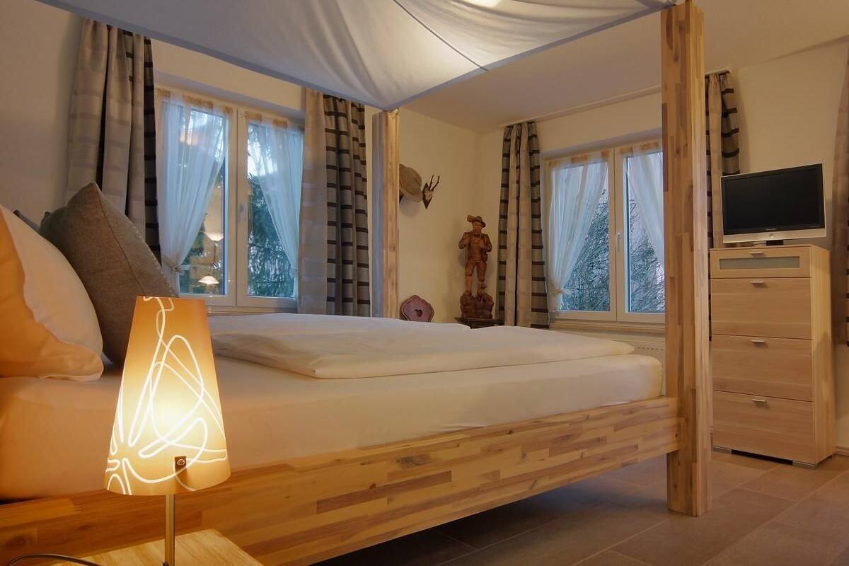 Une chambre à coucher avec un lit en bois, une lampe de chevet, une commode et un téléviseur.