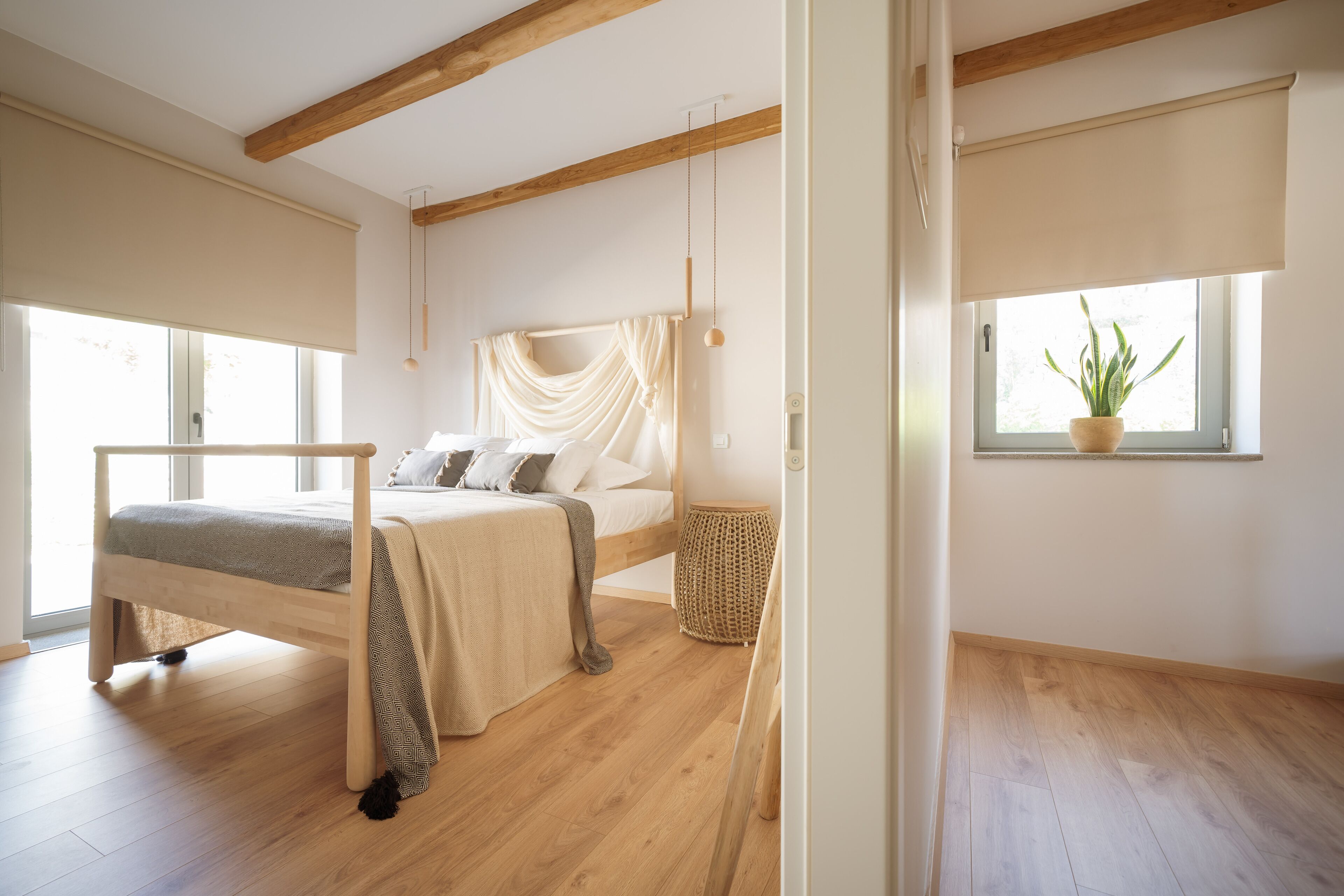 Un dormitorio con cama, mesita de noche y una planta en maceta cerca de la ventana.