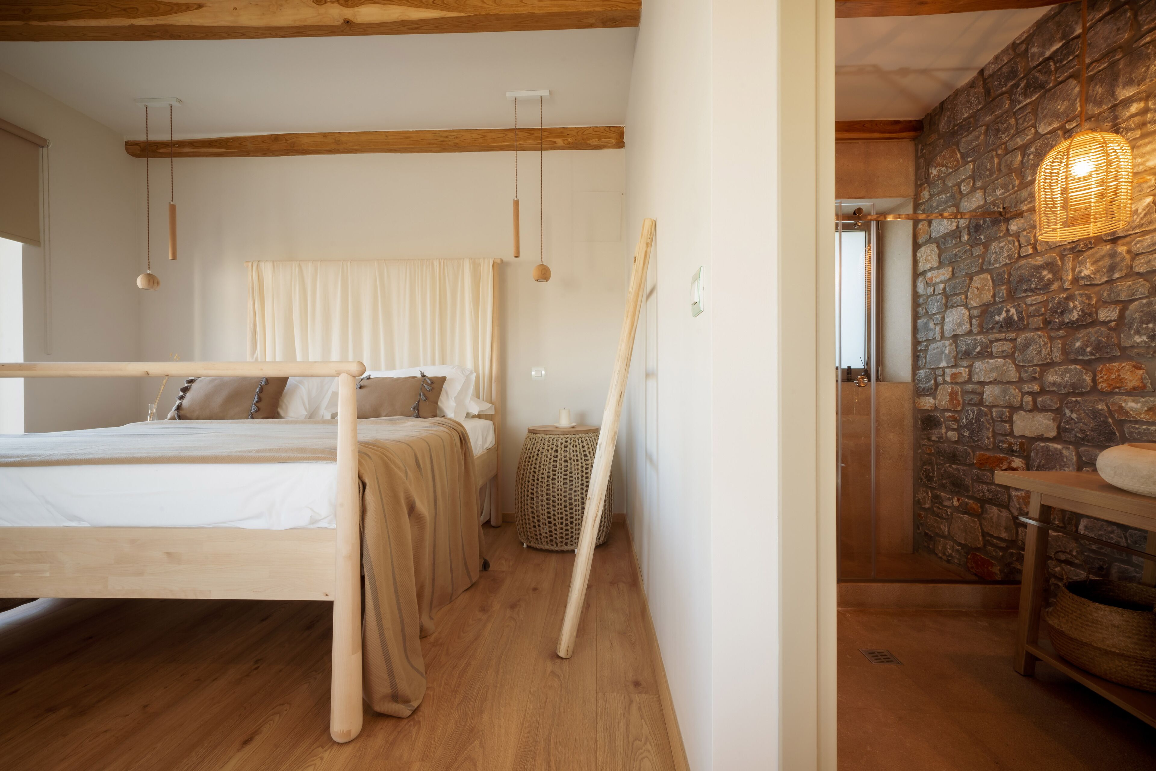 Un dormitorio con cama de madera, pared de piedra y lámpara de fibra.