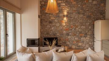 Ein Wohnzimmer mit Steinsandsteinwand, einer Couch mit Kissen, einem Fernseher und einer Weidenlampe.