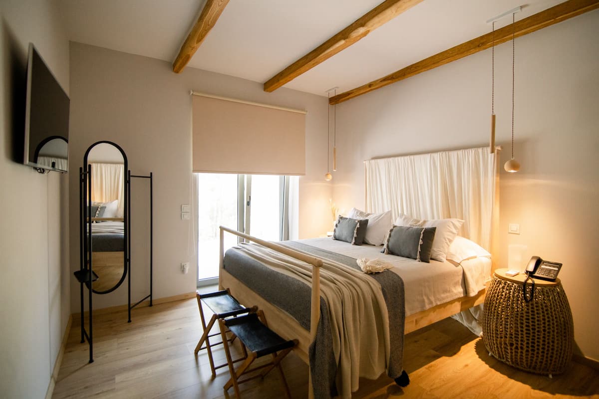 A bedroom with a bed, bedside table, and a window with curtains.