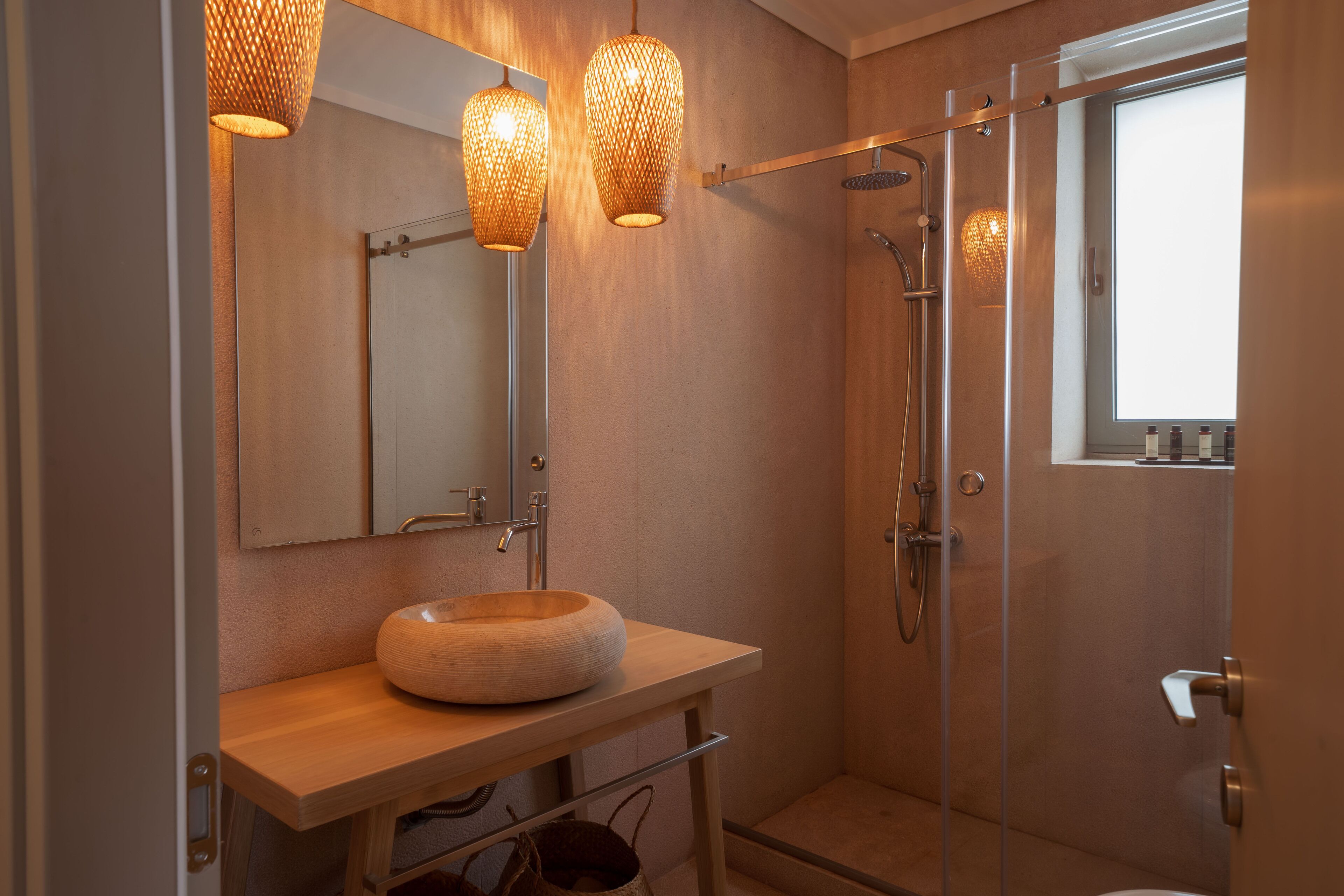 Ein modernes Badezimmer mit einem runden Holzwaschbecken, einer Duschkabine aus Glas und einem großen Spiegel.