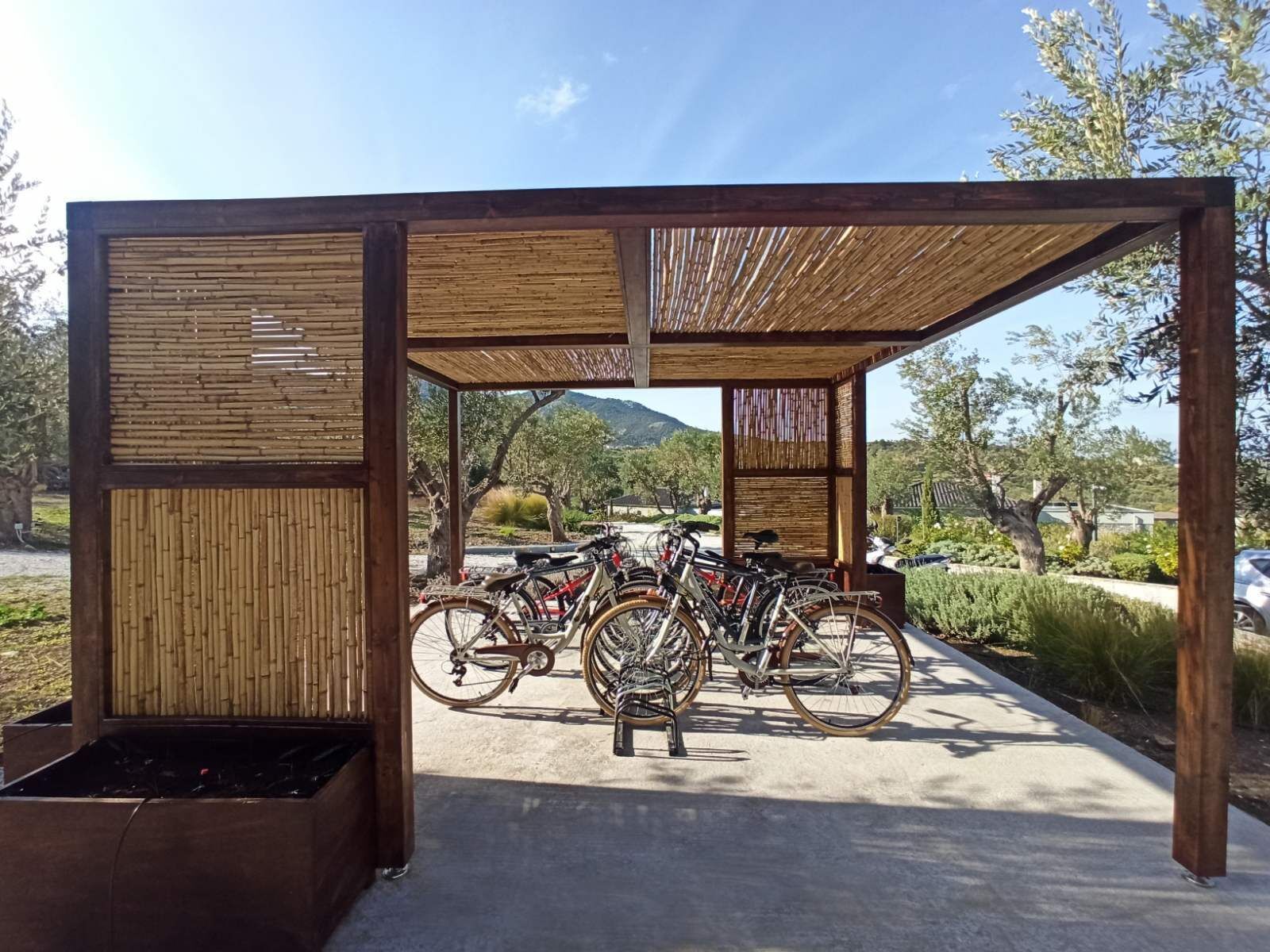 A covered bike parking area with bamboo panels and a concrete floor.