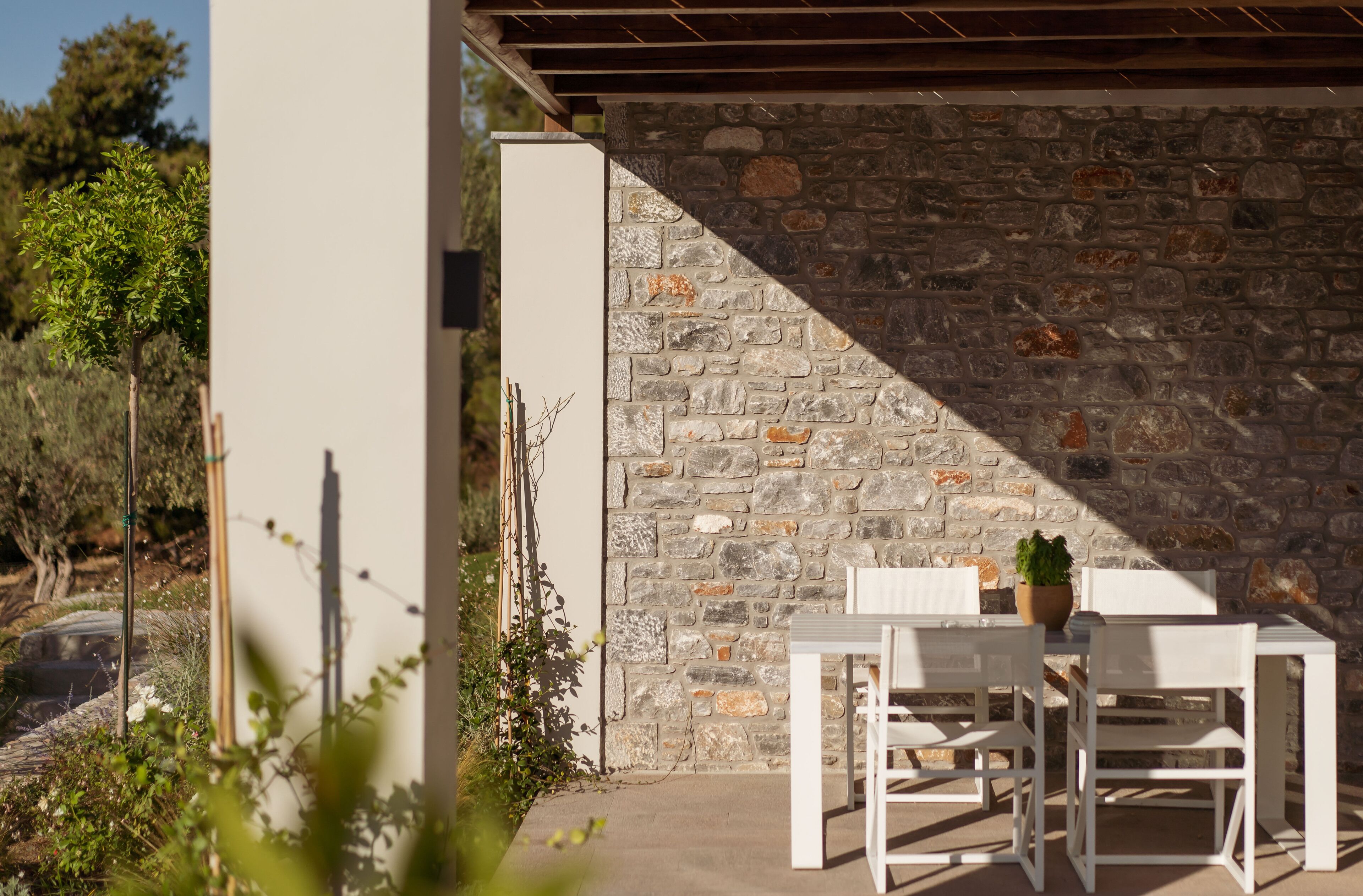 Un muro de piedra con una mesa y sillas frente a un edificio.