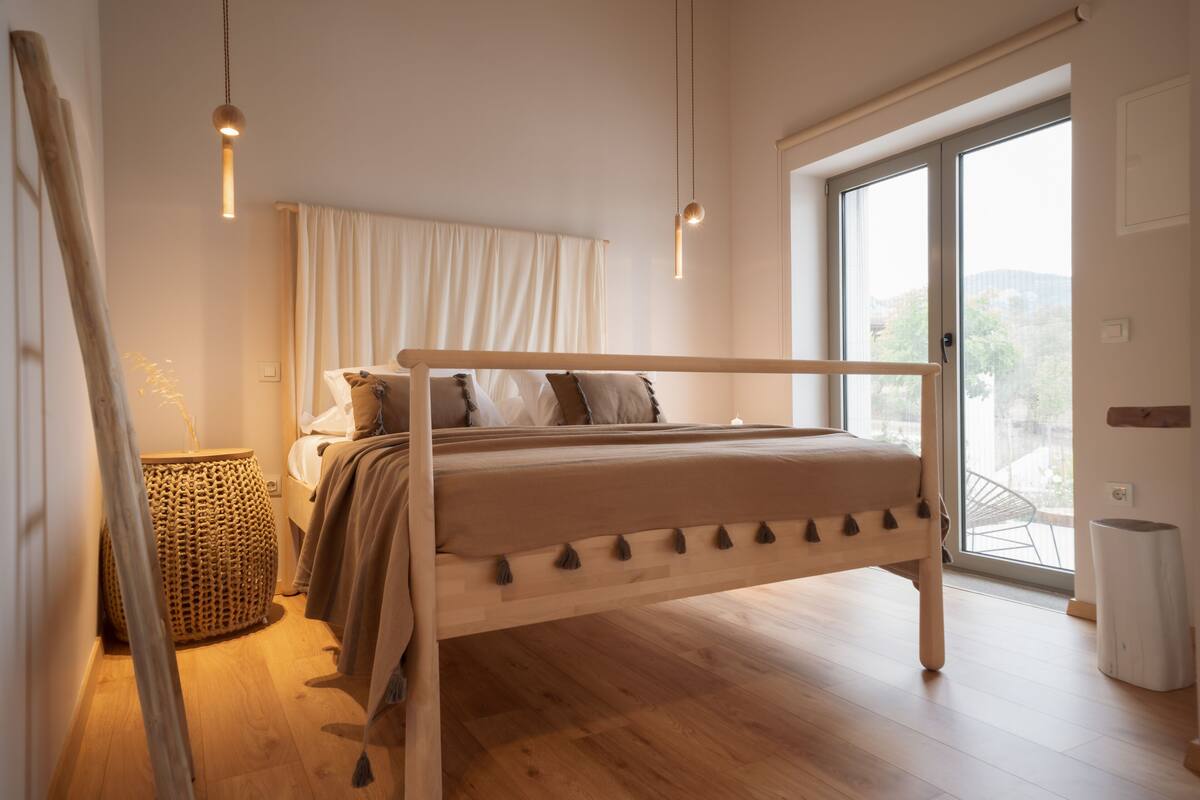 A bedroom with a wooden bed, a large window, and a wicker basket.