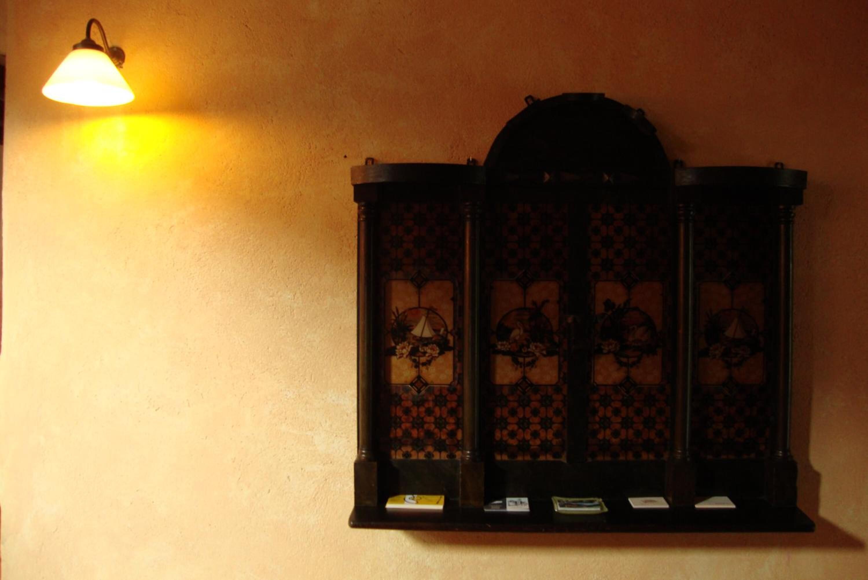 A wall-mounted cabinet with a patterned design and a light fixture above it.