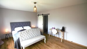 Ein Schlafzimmer mit einem großen Bett, Nachttischen, einem Schreibtisch und einer Pendelleuchte.