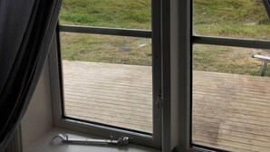 Ein Fenster mit Blick auf eine grüne Landschaft und einen bewölkten Himmel.