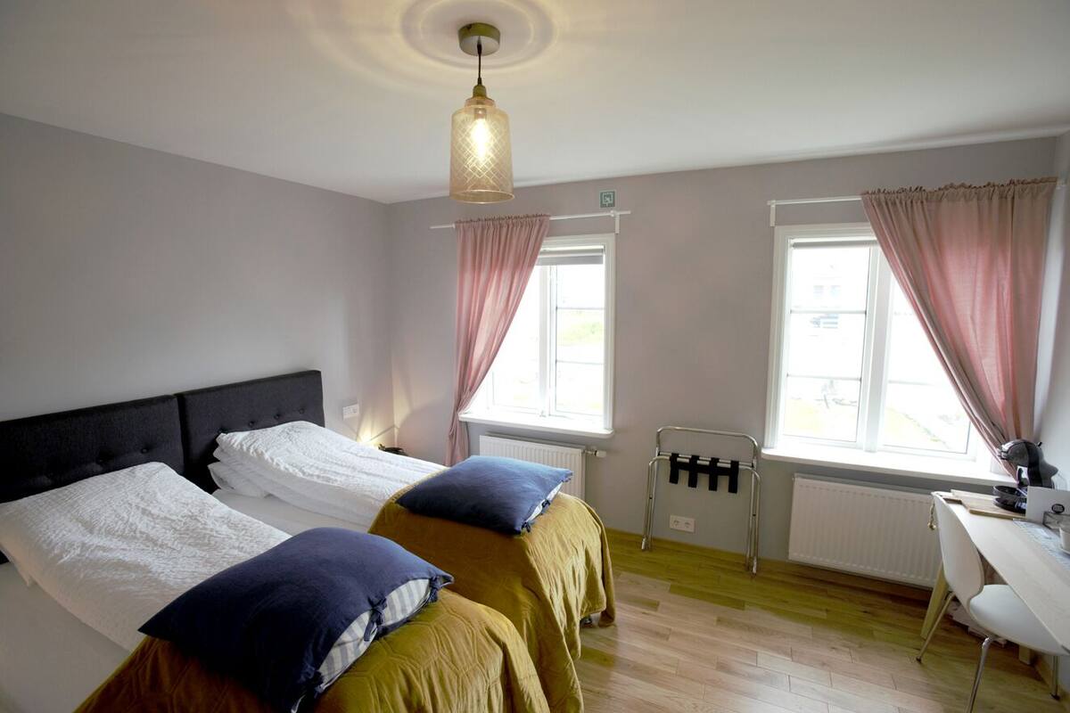 A bedroom with two beds, a desk, and a chair.