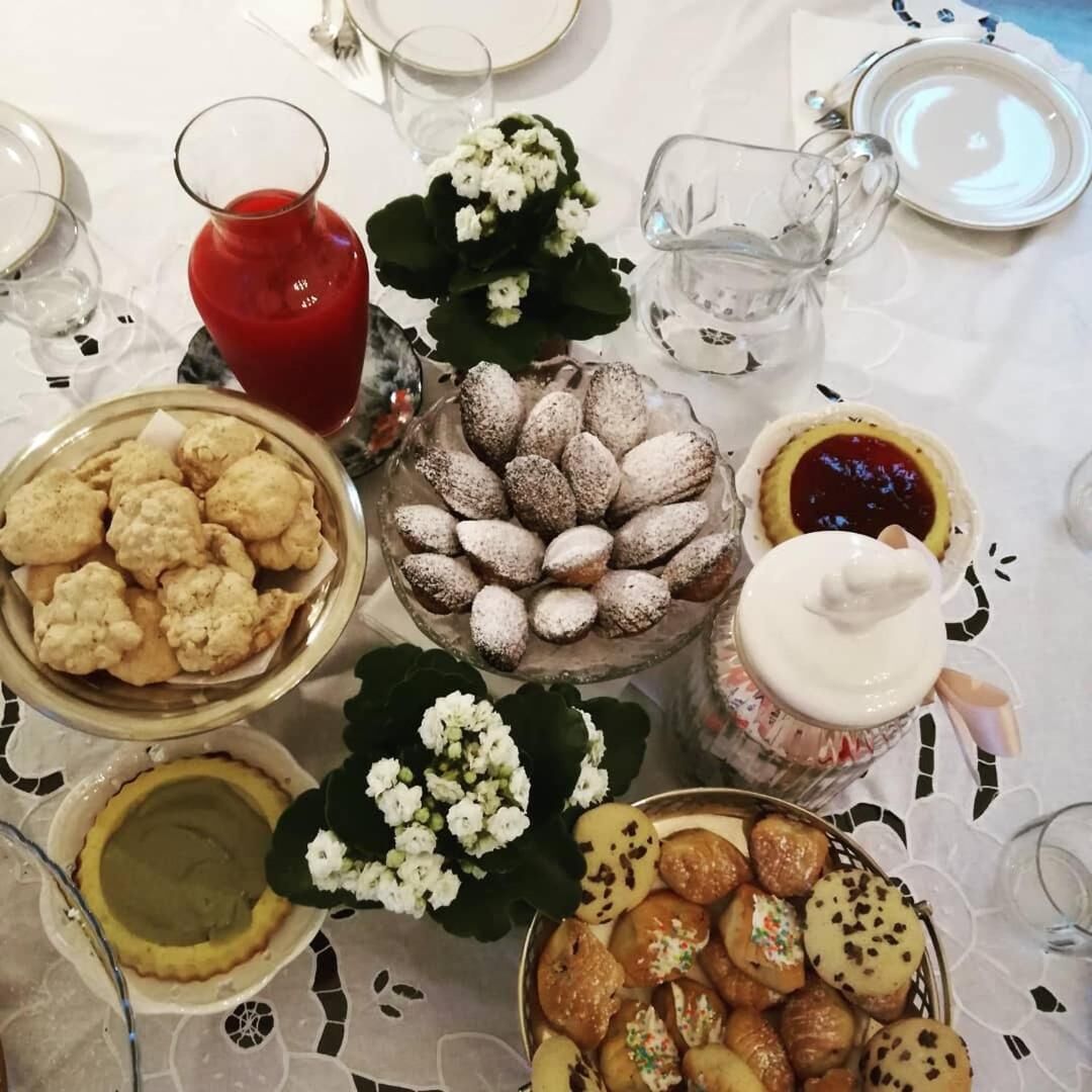 Una mesa dispuesta con diversos postres, incluyendo un cuenco de galletas, un plato de almendras y un tarro de mermelada.
