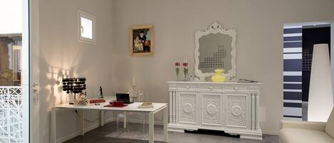 Una habitación con un escritorio blanco, un armario blanco, un cuadro enmarcado y un espejo en la pared.