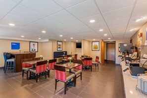 Comedor de hotel con varias mesas y cabinas, mostrador de recepción y zona de cocina.