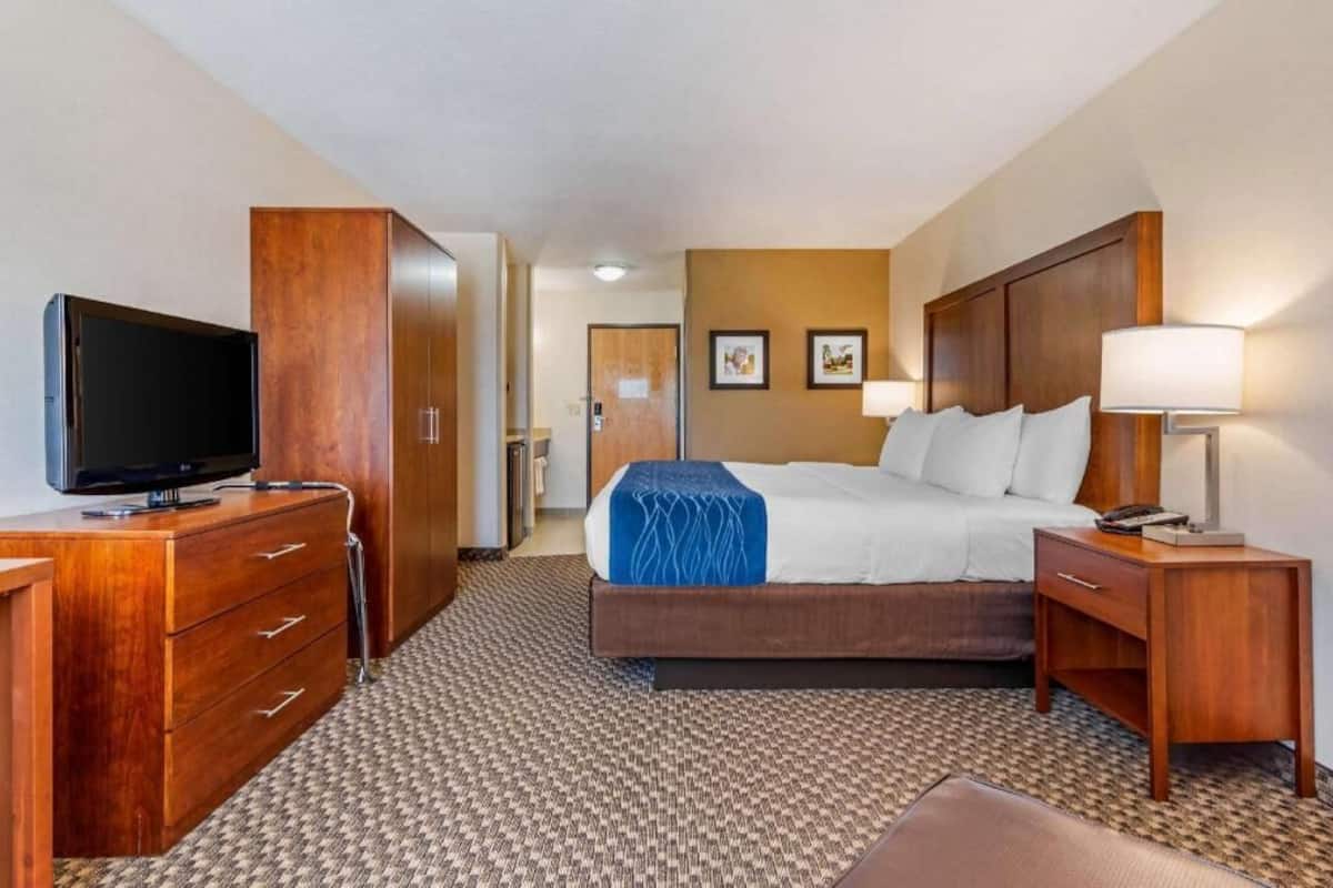 A hotel room with a bed, a TV, a desk, and a wardrobe.