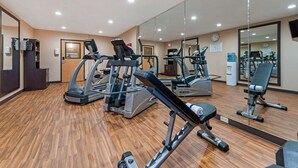 A gym with various exercise machines, wooden flooring, and mirrors on the walls. - Comfort Inn & Suites near Route 66 (Lincoln)