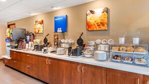 A breakfast buffet with various food items, a coffee station, and a television. - Comfort Inn & Suites near Route 66 (Lincoln)