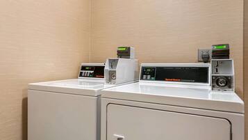 A laundry area with two white washing machines and two dryers, each with digital displays and control panels.