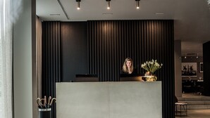 Een moderne receptie met een receptiebalie, zwarte gestoffeerde zitplaatsen en een minimalistische inrichting.