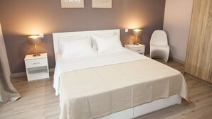 A neatly arranged bedroom with a large bed, two bedside tables, a chair, and two wall-mounted lamps. - Cozy Penthouse - Stunning View Acropolis (Athens)