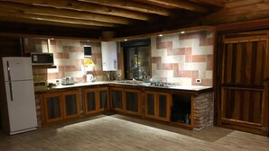 A kitchen with wooden cabinets, a refrigerator, a microwave, and a tiled backsplash. - Cabaña La Emilia (Uspallata)
