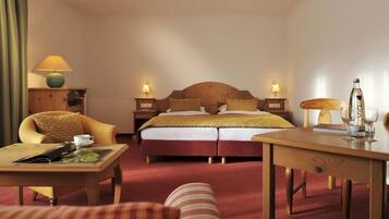 Ein Hotelzimmer mit einem Doppelbett, zwei Nachttischen mit Lampen, einem Holztisch, einem Stuhl und einem Sofa.