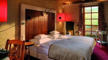 A bedroom with a wooden headboard, a bed with white linens, a red lamp, and a window with patterned curtains.