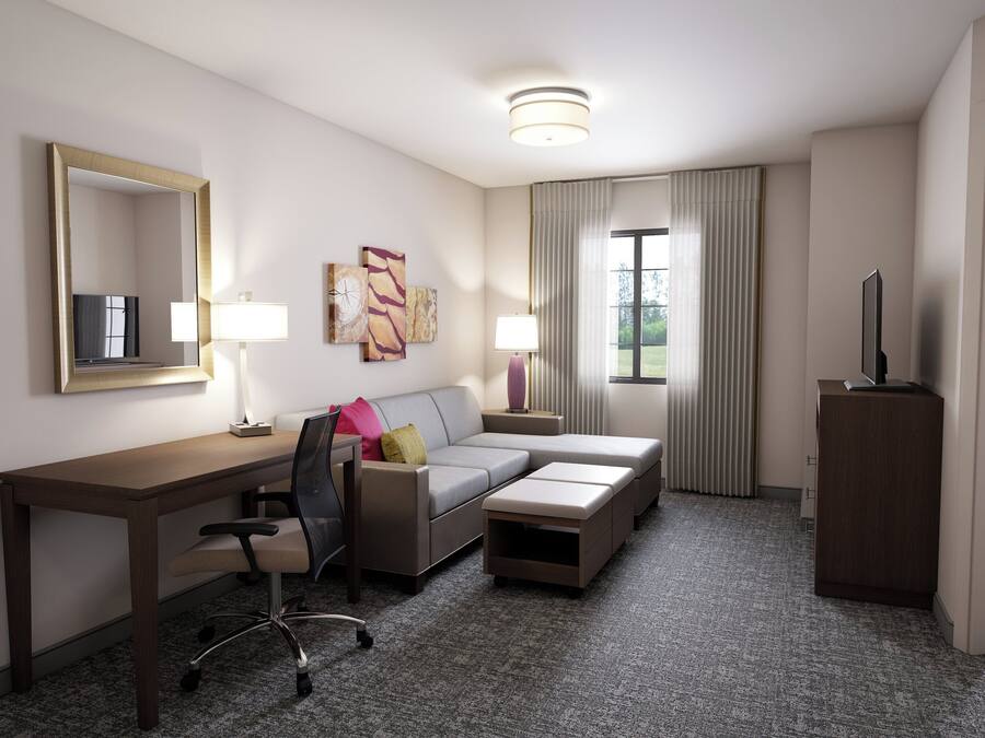 Une chambre d’hôtel équipée d’un bureau, d’un canapé, d’une chaise, d’une télévision et d’une armoire.