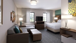 Een hotelkamer met een bank, een bed, een televisie en een bureau met een lamp.