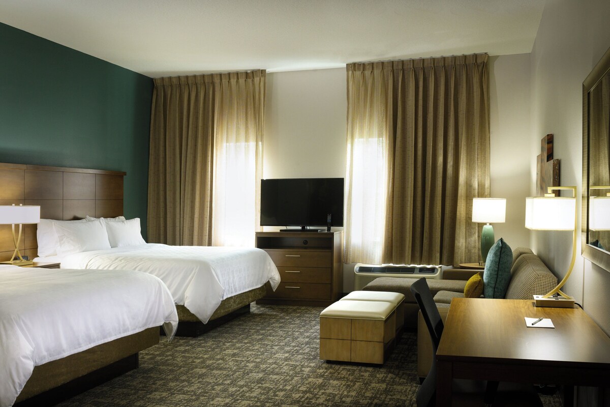 Une chambre d’hôtel avec deux lits, une télévision, un bureau et une chaise.