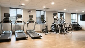 Een fitnessruimte met loopbanden, elliptische trainers en een hometrainer.