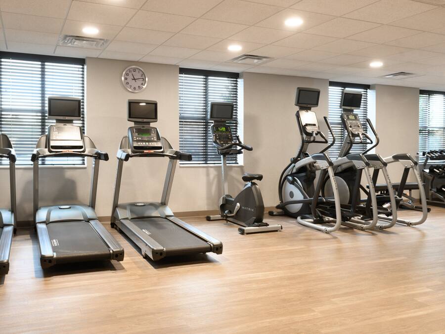 Een fitnessruimte met loopbanden, elliptische trainers en een hometrainer.