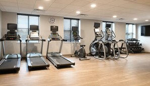 Une salle de sport équipée de tapis de course, de vélos elliptiques et d’un vélo d’appartement.