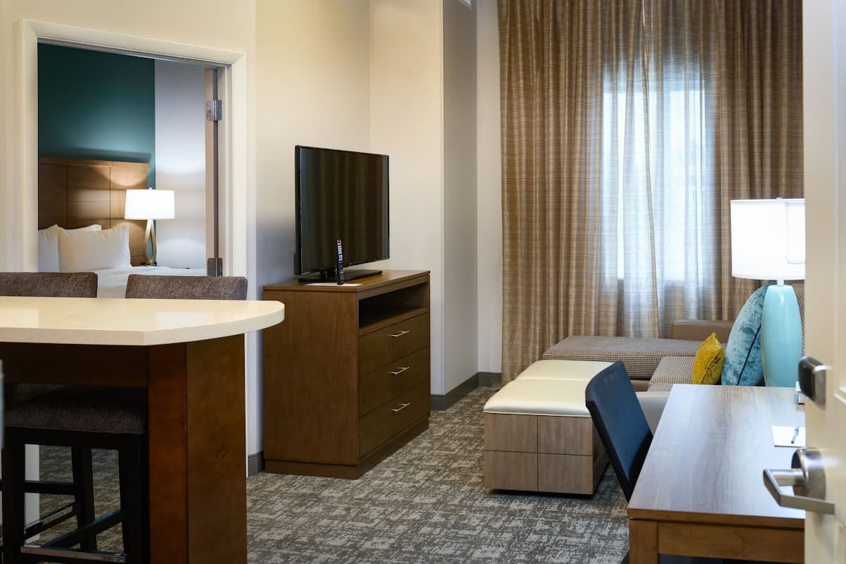 Een hotelkamer met een bed, een bureau, een televisie en een raam met gordijnen.
