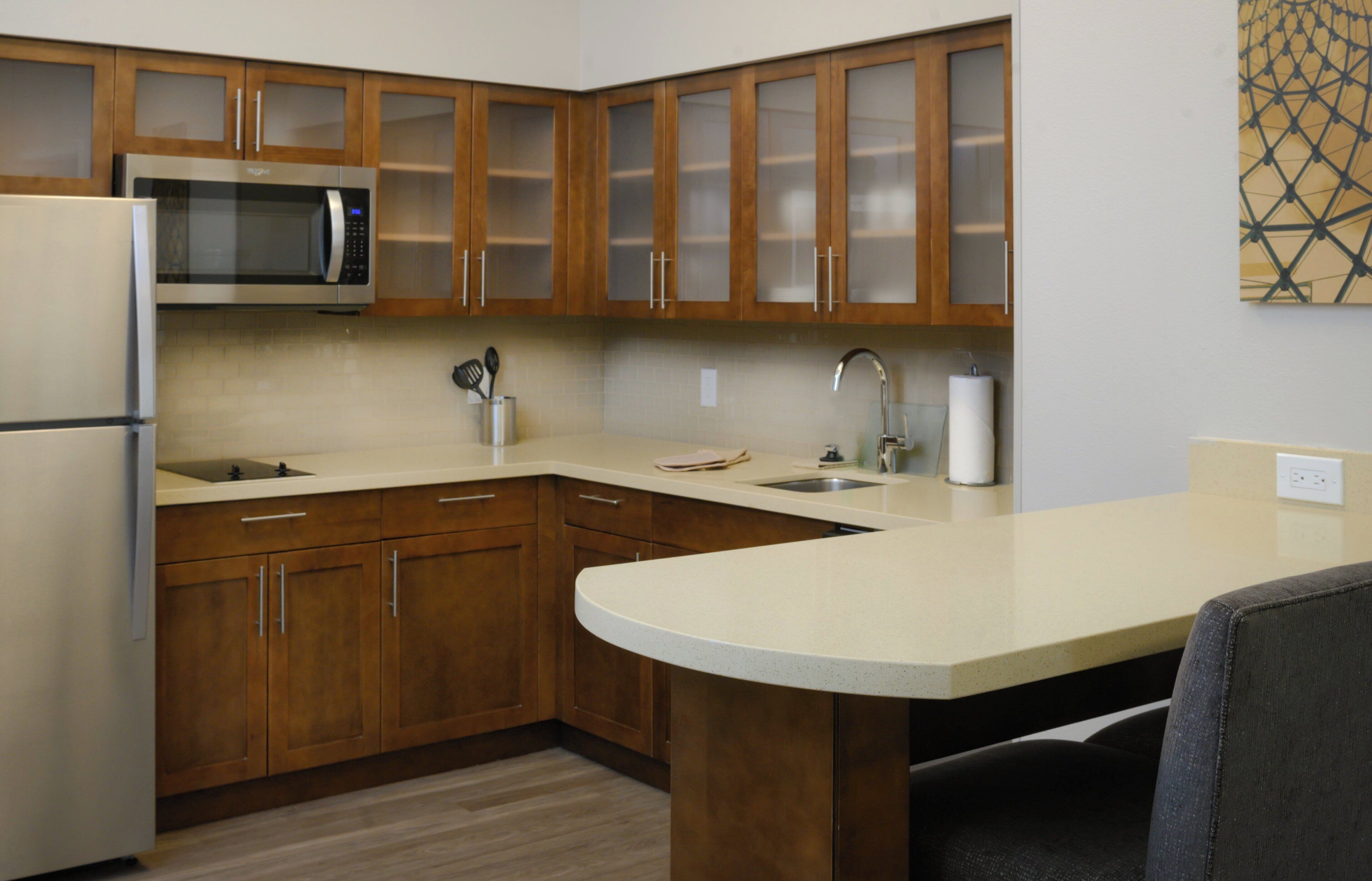 A kitchen with wooden cabinets, a stainless steel microwave, a sink, and a countertop.