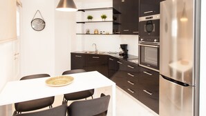 A modern kitchen with dark cabinets, a stainless steel refrigerator, and a white dining table with chairs. - Luxurious Apartment in Athens Downtown (Athens)