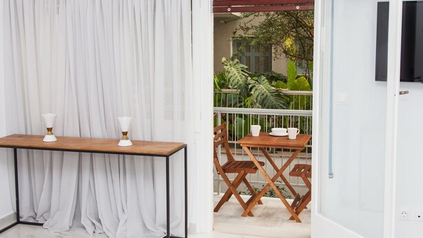 A modern room with a wooden table and chairs, a white curtain, and a view of the outside balcony. - Luxurious Apartment in Athens Downtown (Athens)