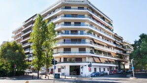 A multi-story building with balconies, a ground entrance, and parked cars. - Luxurious Apartment in Athens Downtown (Athens)