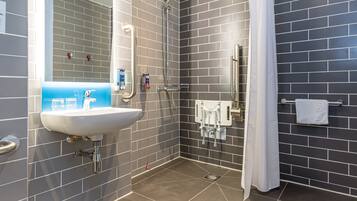 Un baño moderno con un lavamanos blanco, una ducha con puerta de cristal y un perchero para toallas.