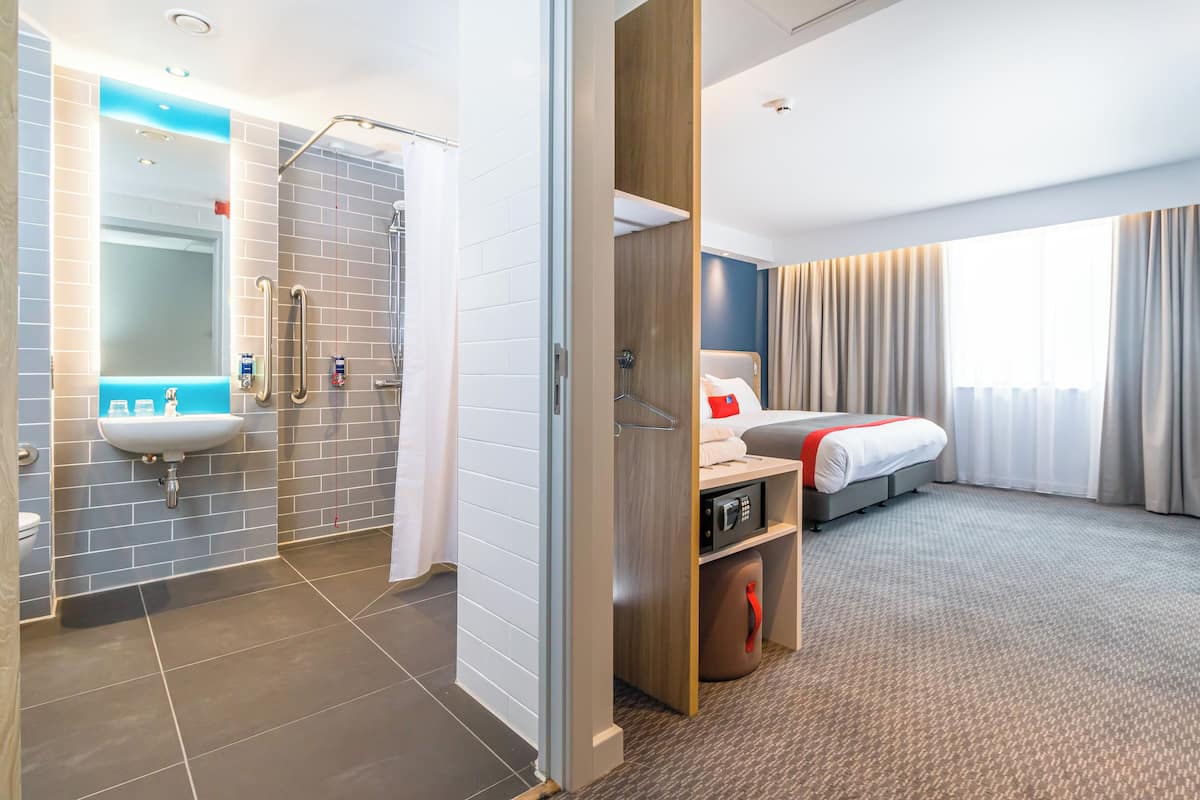 Una habitación de hotel con baño, cama y vista a la ciudad.