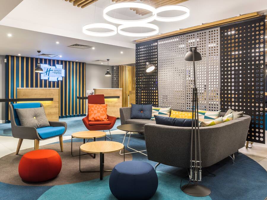 A modern hotel lobby with a reception desk, seating area, and decorative lighting.