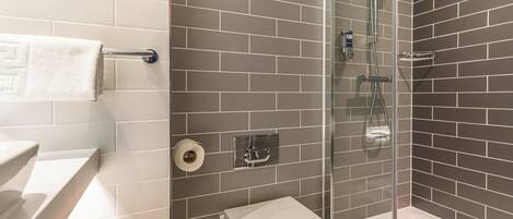 A bathroom with a glass-enclosed shower, a toilet, and a towel rack.