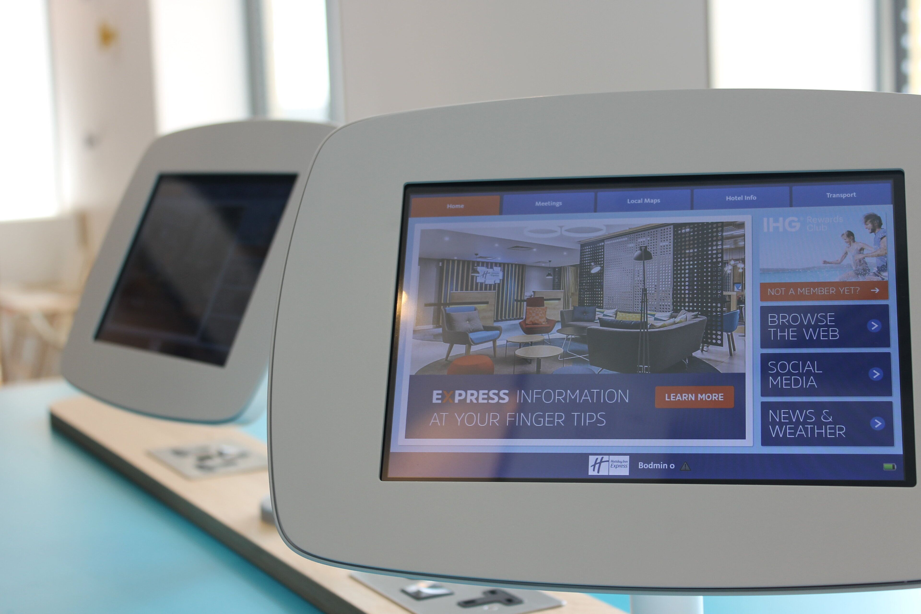 Two digital kiosks with screens displaying hotel information and options.