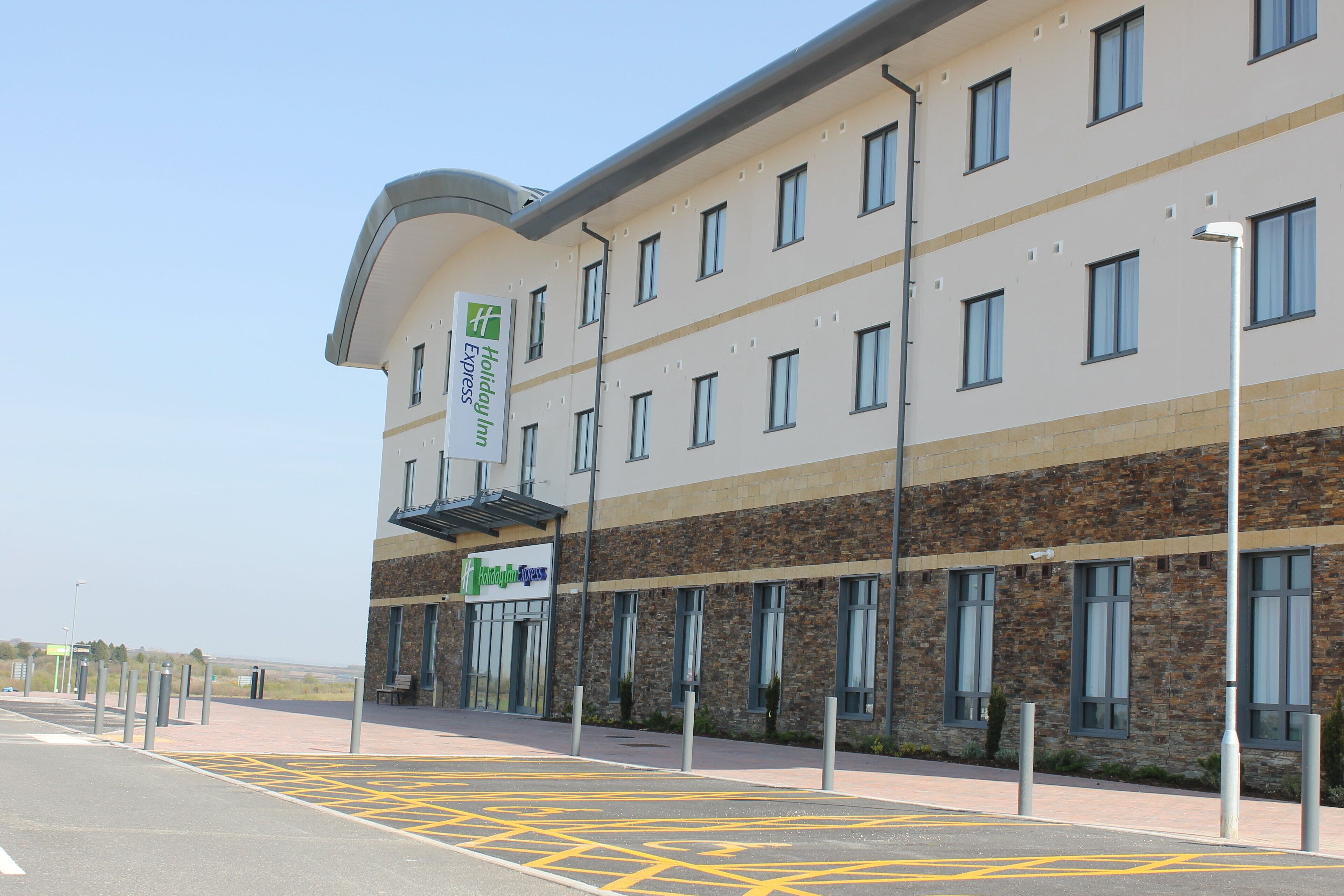 Edifício Holiday Inn Express com design moderno, apresentando fachada de pedra e várias janelas.